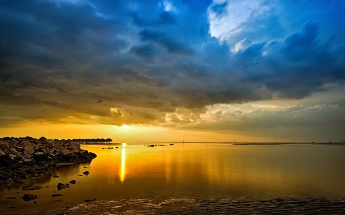 Sunset over the ocean with rocky shore