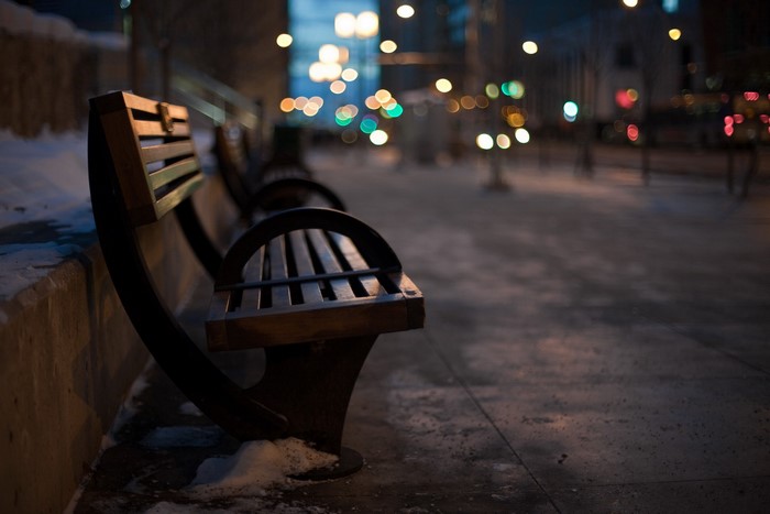 Empty park bench at night with city lights