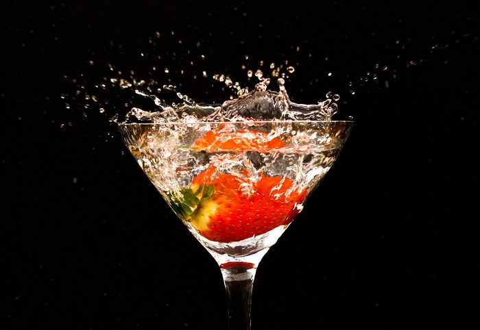 Strawberry splashing into a martini glass