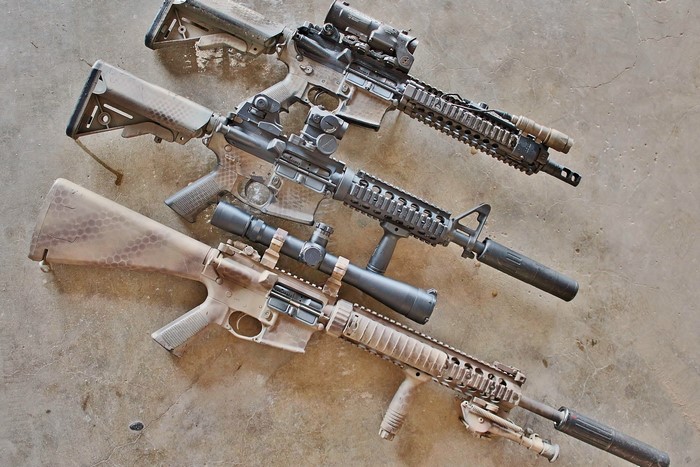 Three AR-15 rifles with scopes and suppressors