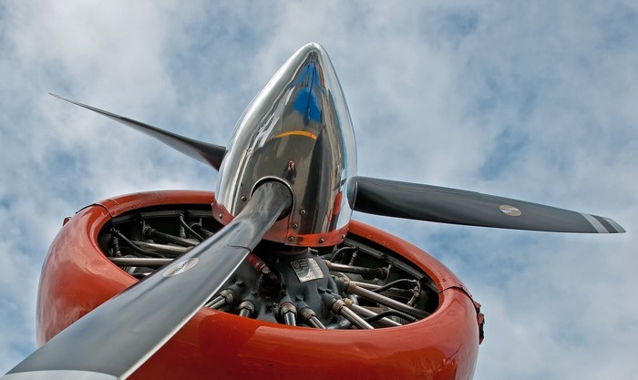 Airplane propeller and engine against a cloudy sky