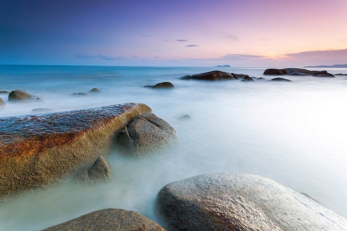 Ocean waves crashing on rocks at sunset