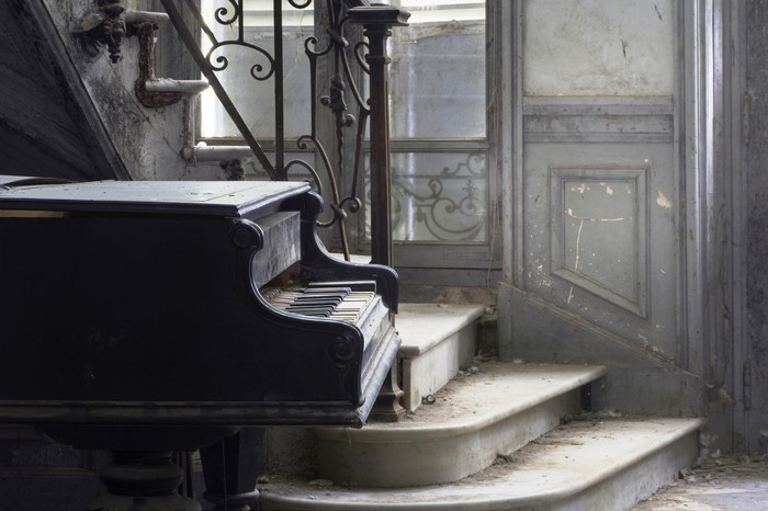Abandoned grand piano on dusty stairs