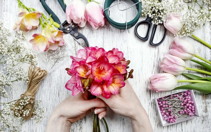 Florist arranging bouquet with tulips and freesia