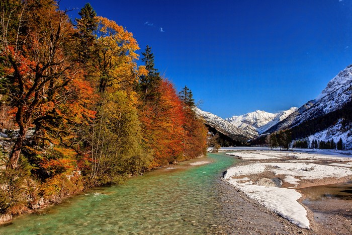 Autumn forest river and snow-capped mountains