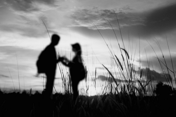 Silhouettes of a couple holding hands at sunset