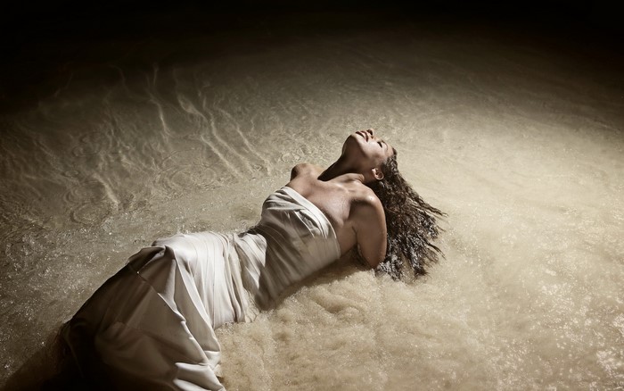 Woman in white dress lying in water