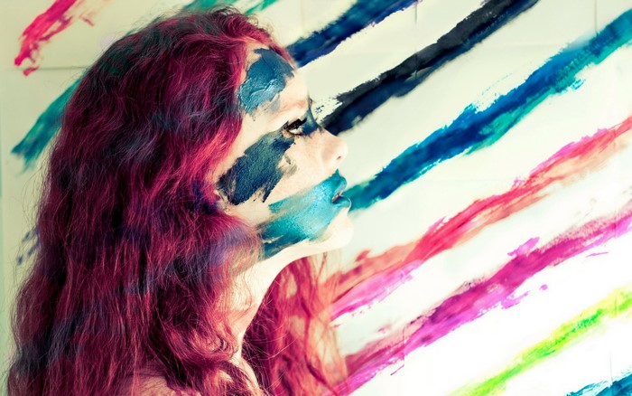 Woman with paint on her face and colorful stripes