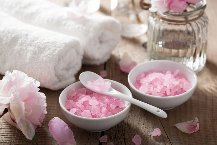 Spa setting with pink salt, towels, and flowers