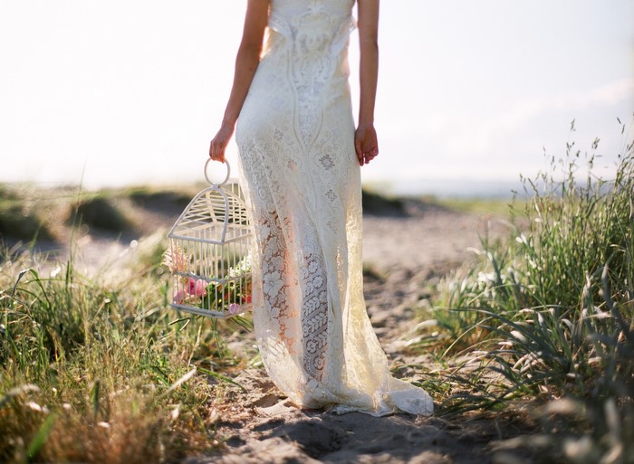 Woman in lace dress holding a birdcage with flowers