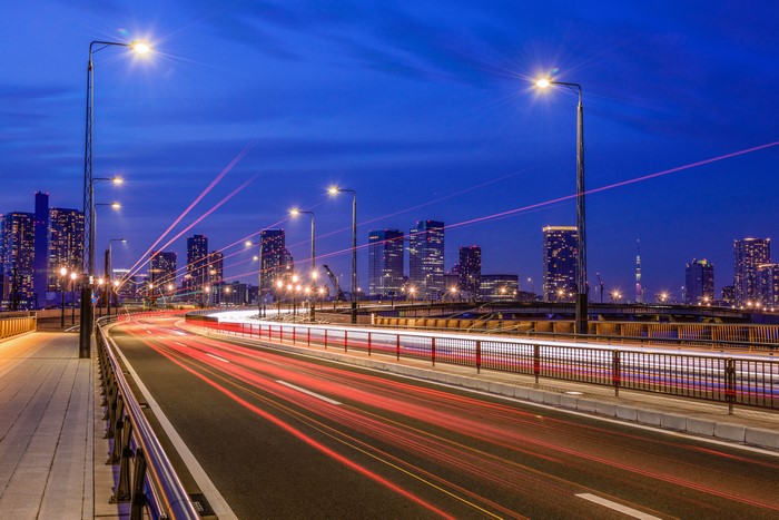Tokyo cityscape at night with light trails on a bridge
