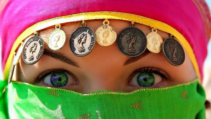 Woman with green eyes and coins on forehead