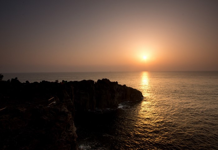 Sunset over the sea with rocky cliffs