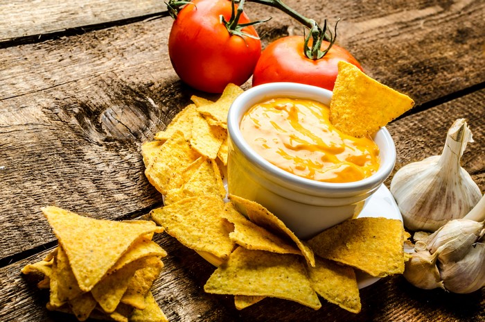 Nachos with cheese dip, tomatoes, and garlic