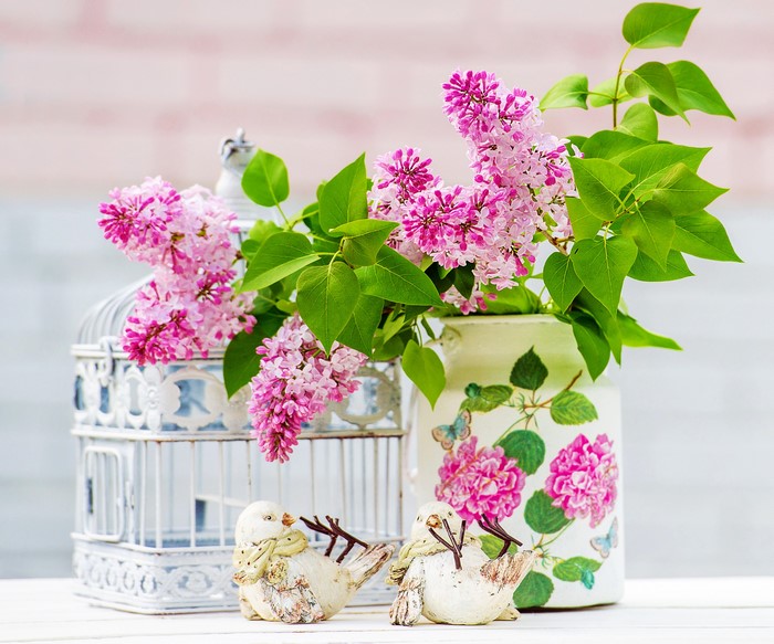 Still-life with lilac flowers in a vase and decorative birds