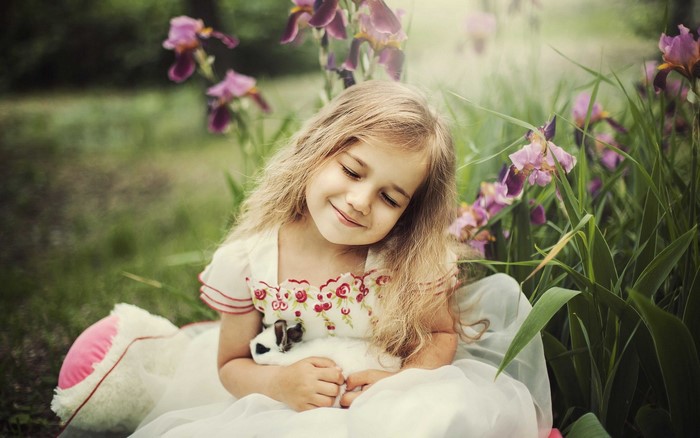 Little girl holding a rabbit in a garden