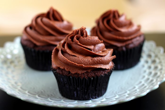 Three chocolate cupcakes with frosting on a plate