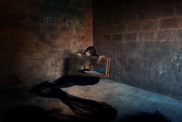 Girl holding a framed painting in a dark room
