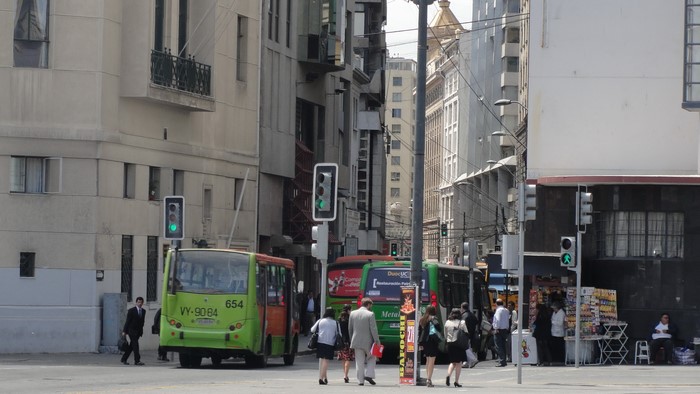 Buses and people at a street intersection in Valparaiso, Chile