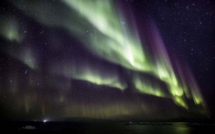 Aurora Borealis over a dark landscape and starry sky