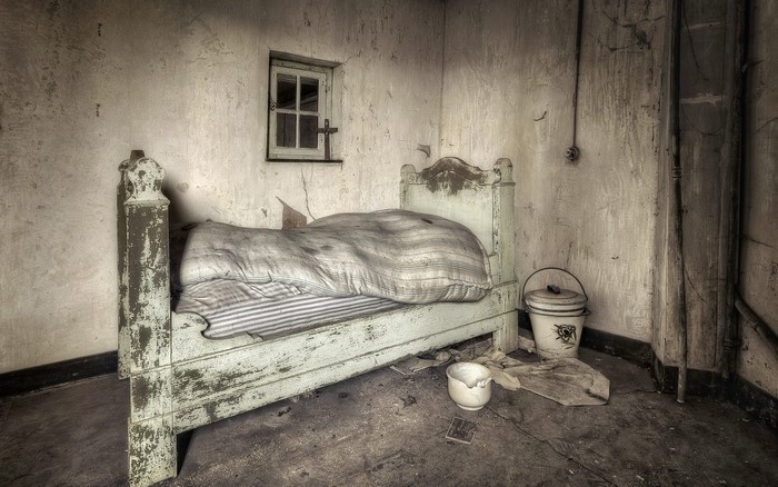 Old room with a bed and a small window