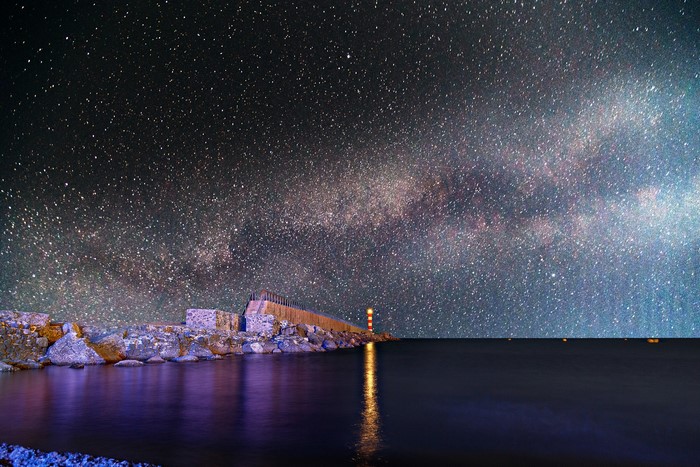 Milky Way over a lighthouse and rocky shore