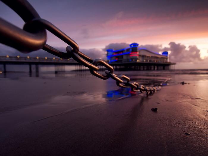 Chain on a beach with a pier at sunset
