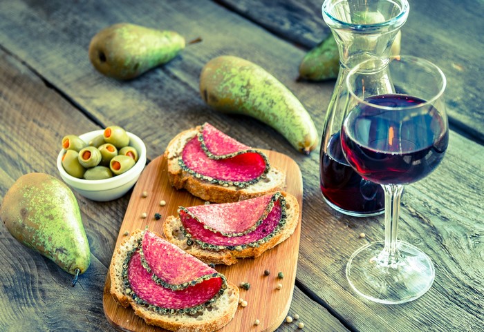 Salami sandwiches with olives, pears, and red wine