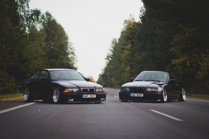 Two black BMW M3 E36 cars on a road