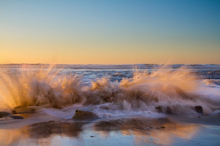 Waves crashing on rocks at sunset