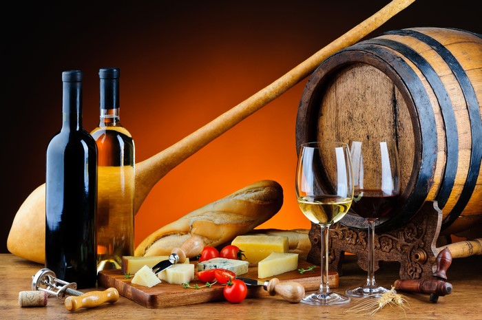 Wine bottles, glasses, cheese, bread, and barrel