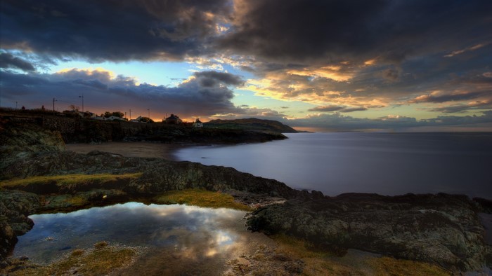 Rocky coast with calm sea and dramatic sunset sky