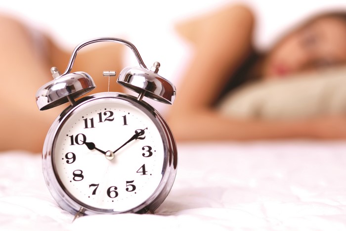 Alarm clock in front of sleeping woman