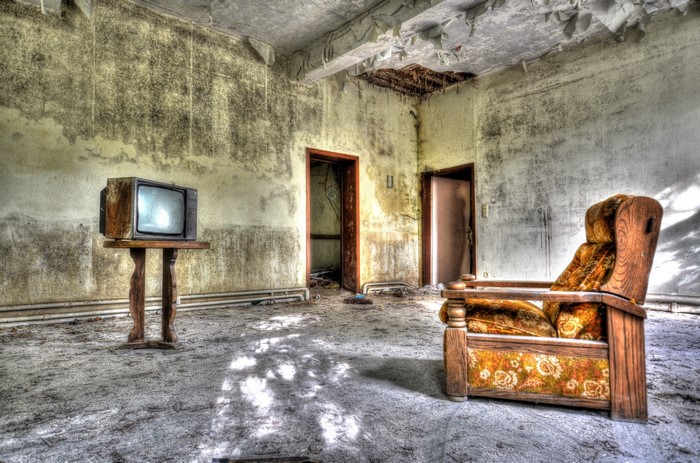 Old TV set and armchair in a derelict room