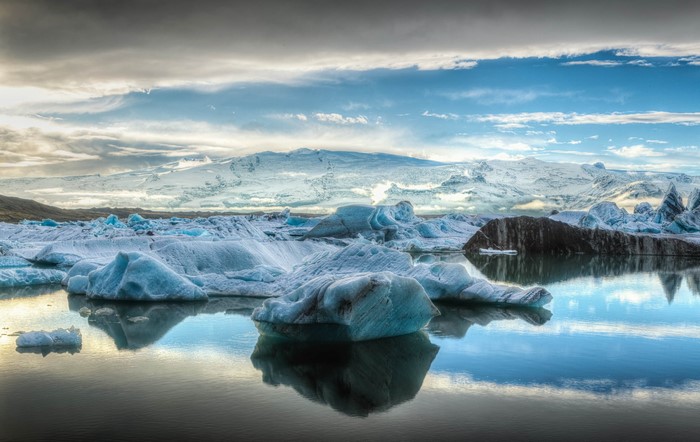 Icebergs floating in a glacial lagoon with snow-capped mountains