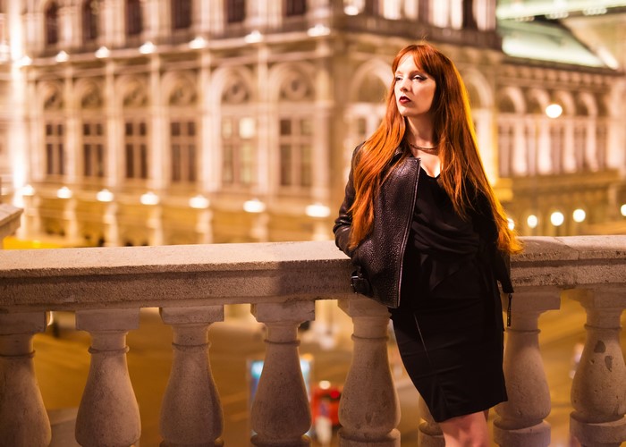 Redhead woman in black dress and jacket at night