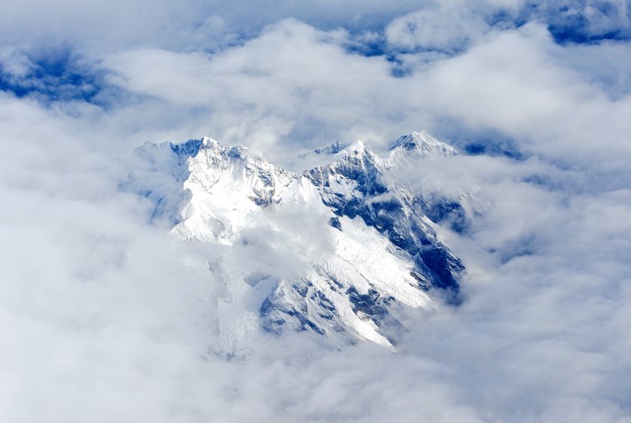 Snow-capped mountains emerge from clouds