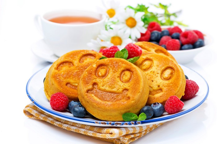 Smiley face waffles with berries and tea