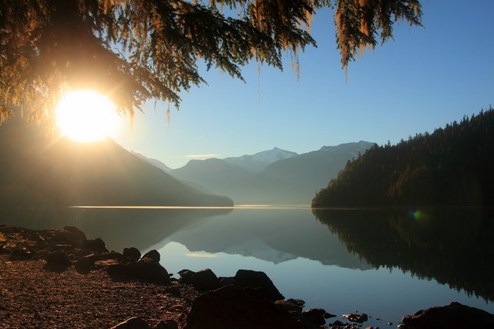 Sunrise over a misty mountain lake with trees