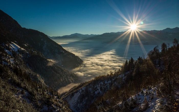 Sunrise over a foggy mountain valley with sun rays