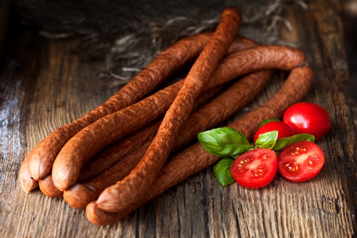 Sausages with tomatoes and basil on a wooden table