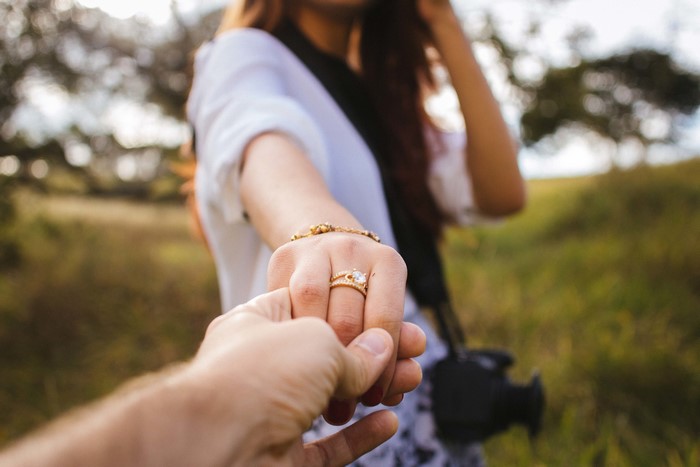 Couple holding hands with engagement ring