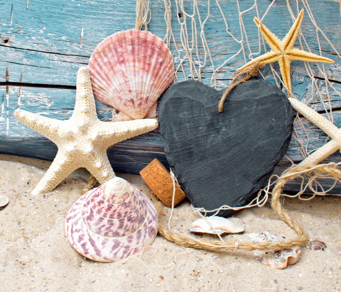 Starfish and shells on sand with heart