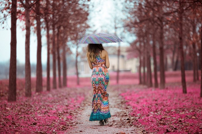 Woman with umbrella walking down an avenue