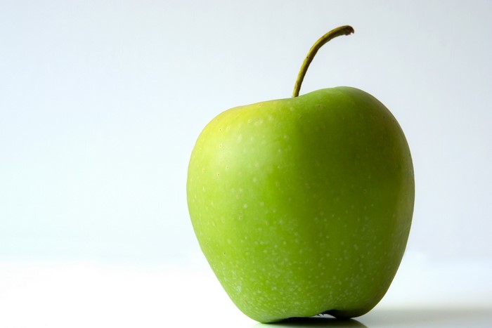 Green apple with stem on white background