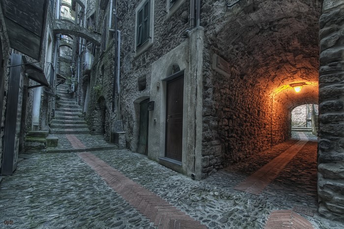 Stone alleyway with stairs and an illuminated tunnel
