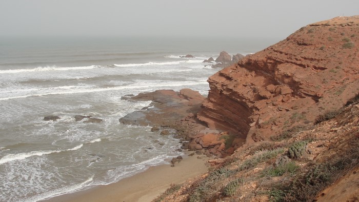 Red rocky coast and ocean waves in Morocco
