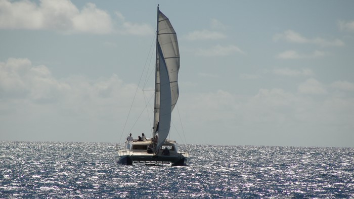 Catamaran sailing on the ocean under a cloudy sky