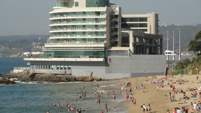 People on a beach in front of a modern hotel in Valparaiso, Chile