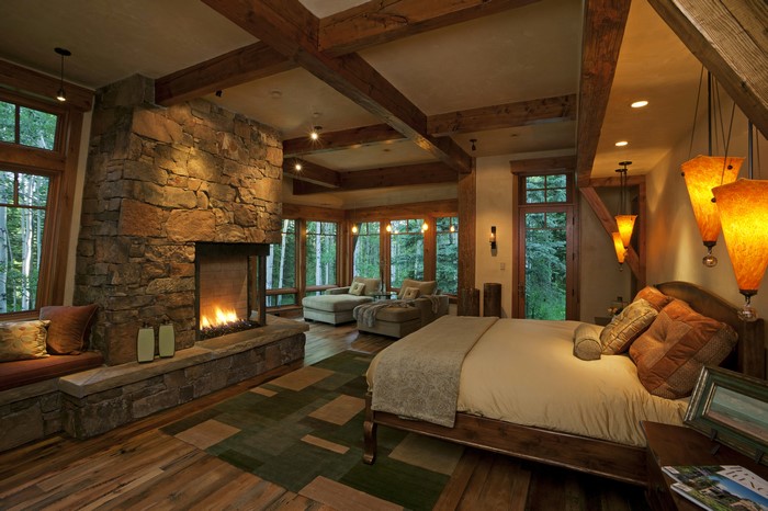 Bedroom with stone fireplace and forest view
